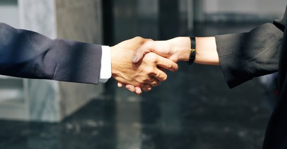 Close-up image of businessman and businesswoman shaking hands after meeting